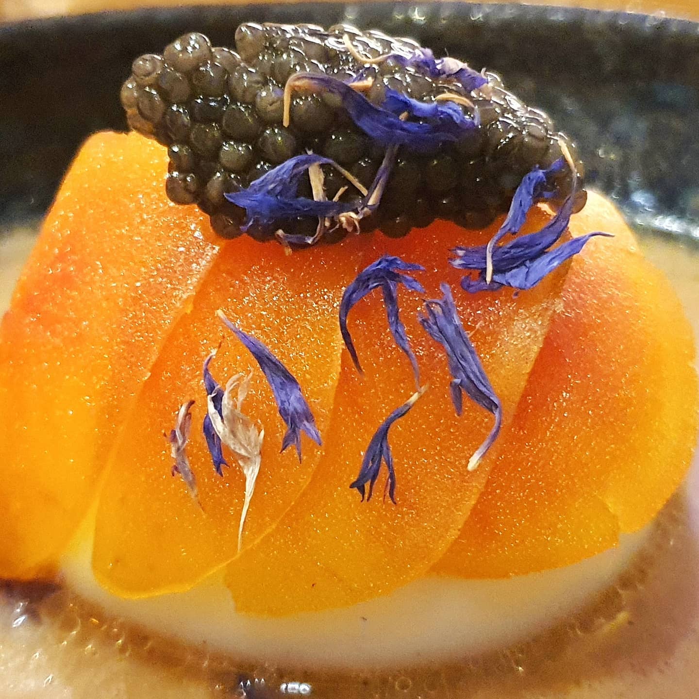 Œuf parfait aux écailles de poutargue, caviar en quenelle et fleurs de bleuet, bouillon aux cèpes.